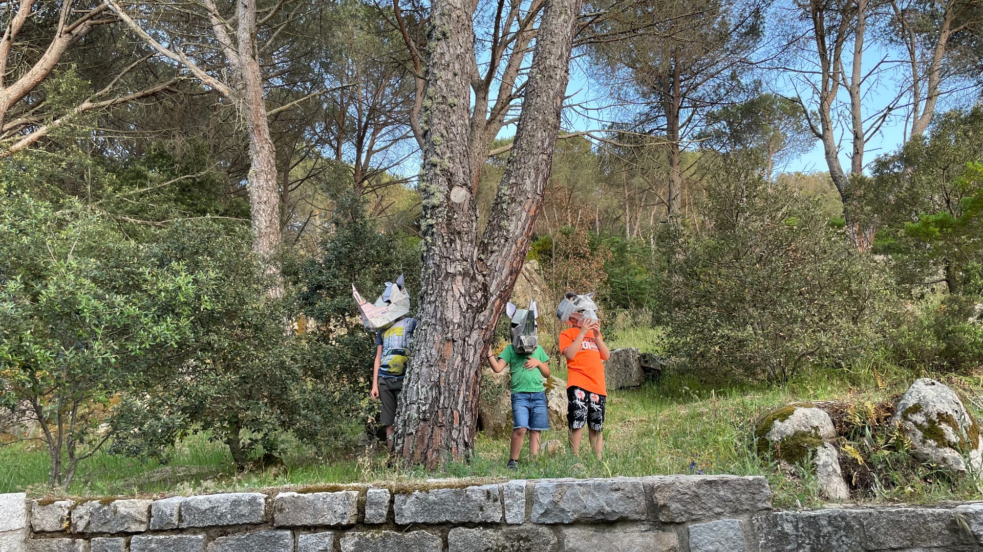bambini con delle maschere di cartapesta giocano tra gli alberi